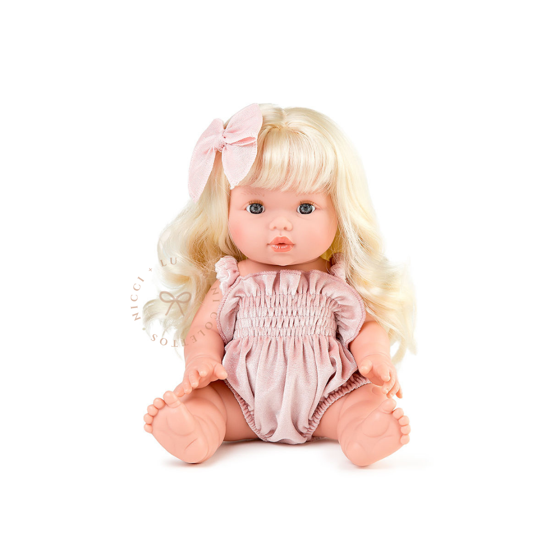 Sage looks adorable dressed in a delicate cotton candy pink smocked bubble romper with a matching linen fable hair bow. Her long blonde curls complete the sweet look, showcasing how beautifully the 34cm Mini Colettos doll can be styled with doll clothing and accessories.