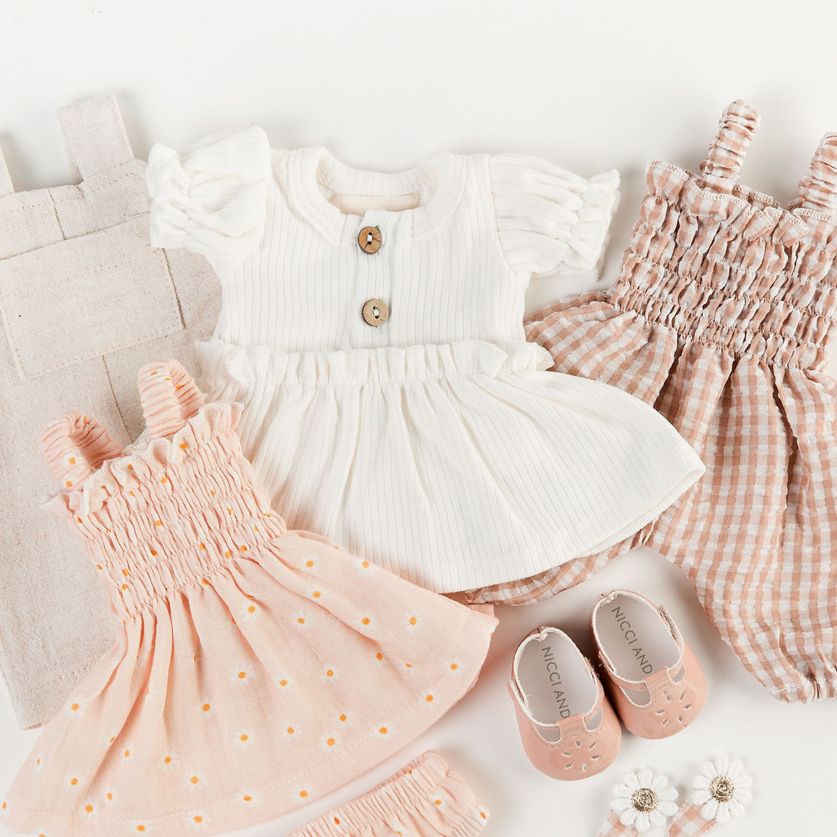 Flat lay of Kennedy puff sleeve dress in ivory, smocked doll outfits and mary jane shoes for 34cm dolls by Nicci and Lu.