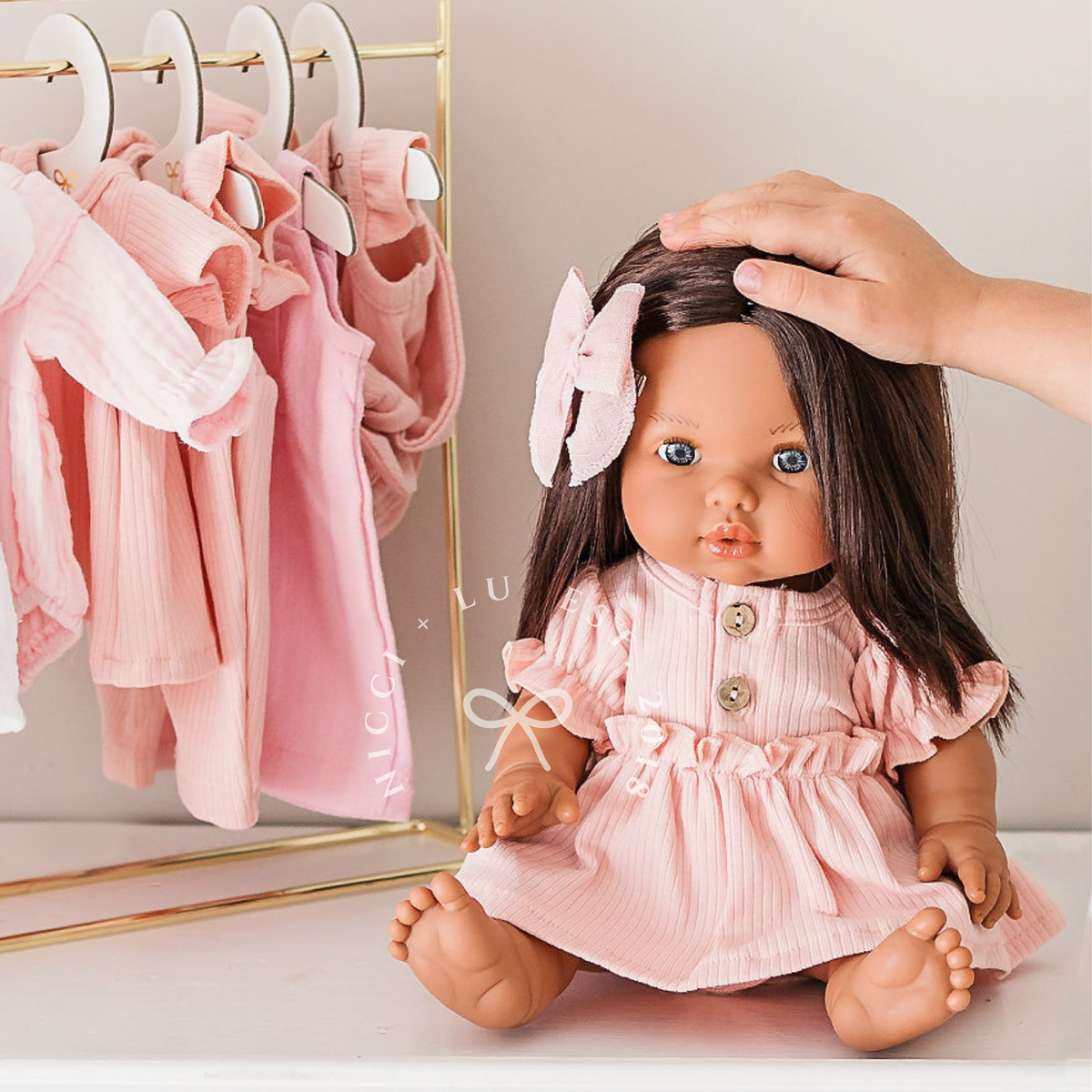 Close-up of 34cm Mini Colettos Isabel brunette doll with blue eyes wearing rose pink puff sleeve dress by Nicci and Lu for 34-38cm doll clothing.