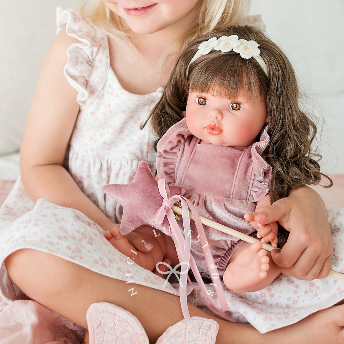 Mini Colettos Hailee wearing the Rose Blush Frilled Bubble Playsuit while being cuddled.