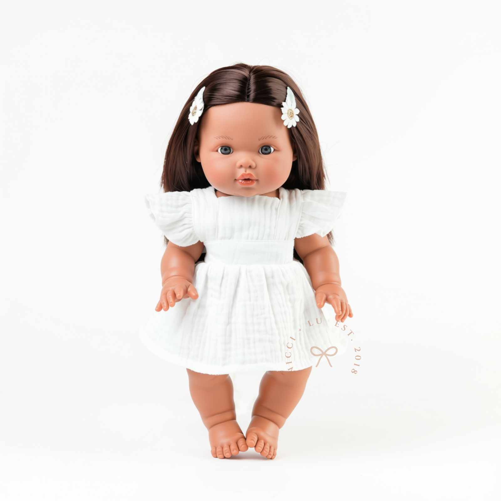 Flat lay of the Ivory Pippa Apron Dress for Mini Colettos, Minikane and other compatible 34cm dolls.