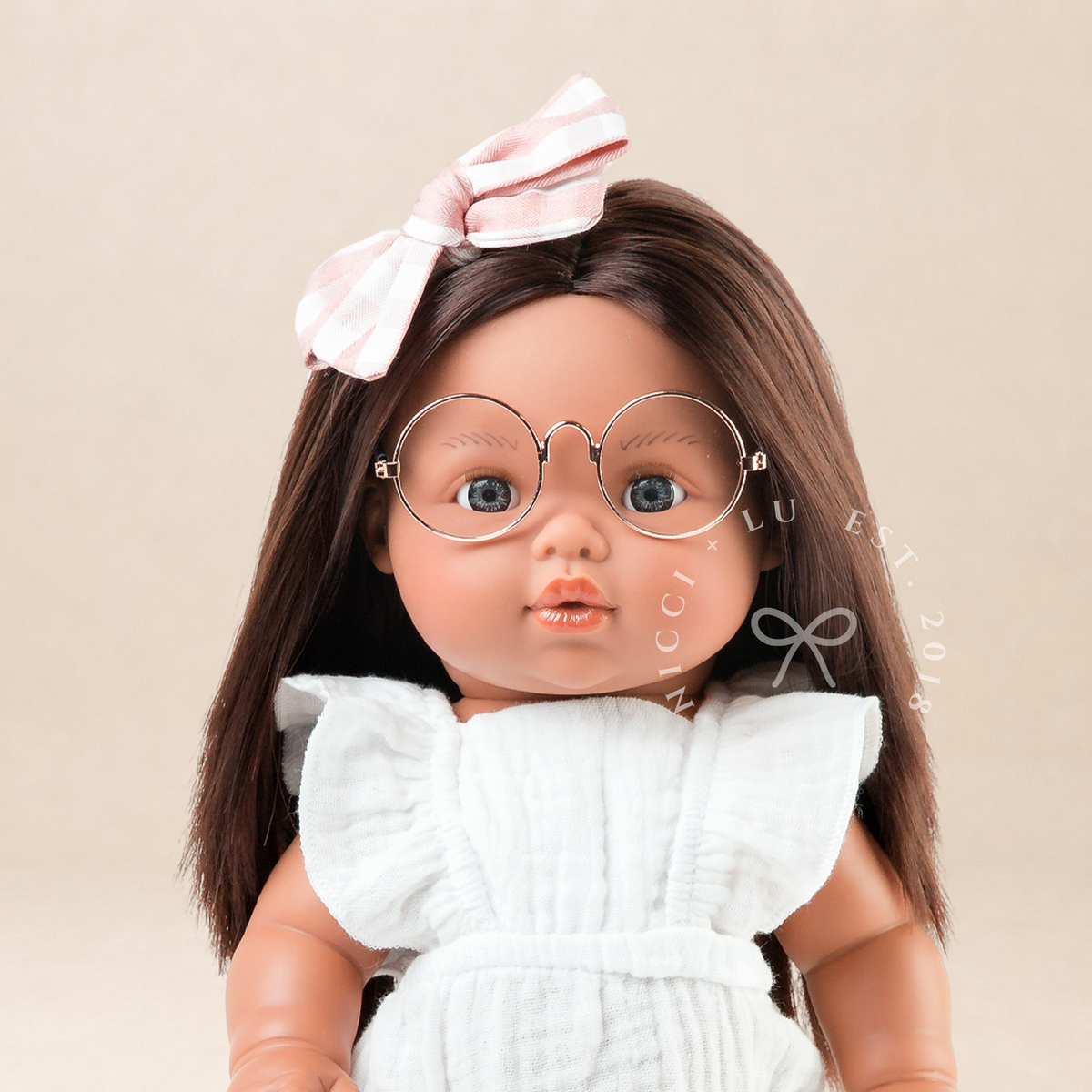 Portrait of 34cm Mini Colettos Isabel wearing the Flutter Romper in Ivory with Soft Pink Mary Jane Shoes.