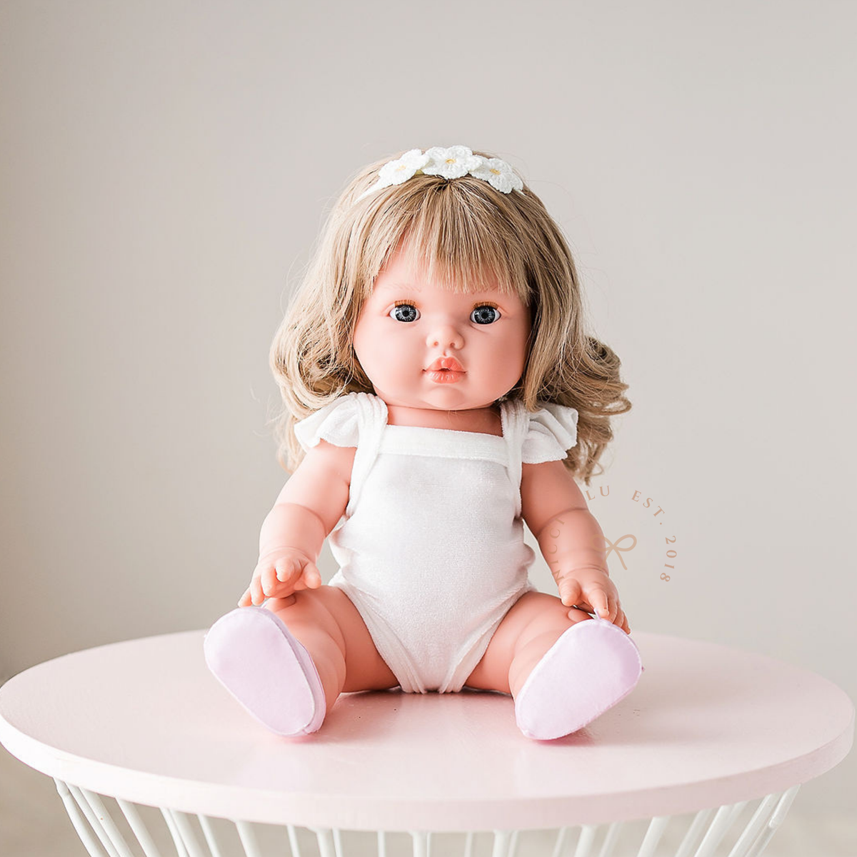 Mini Colettos Kate wearing the Ivory Frilled Velvet Singlet Bodysuit while sitting on a white table.