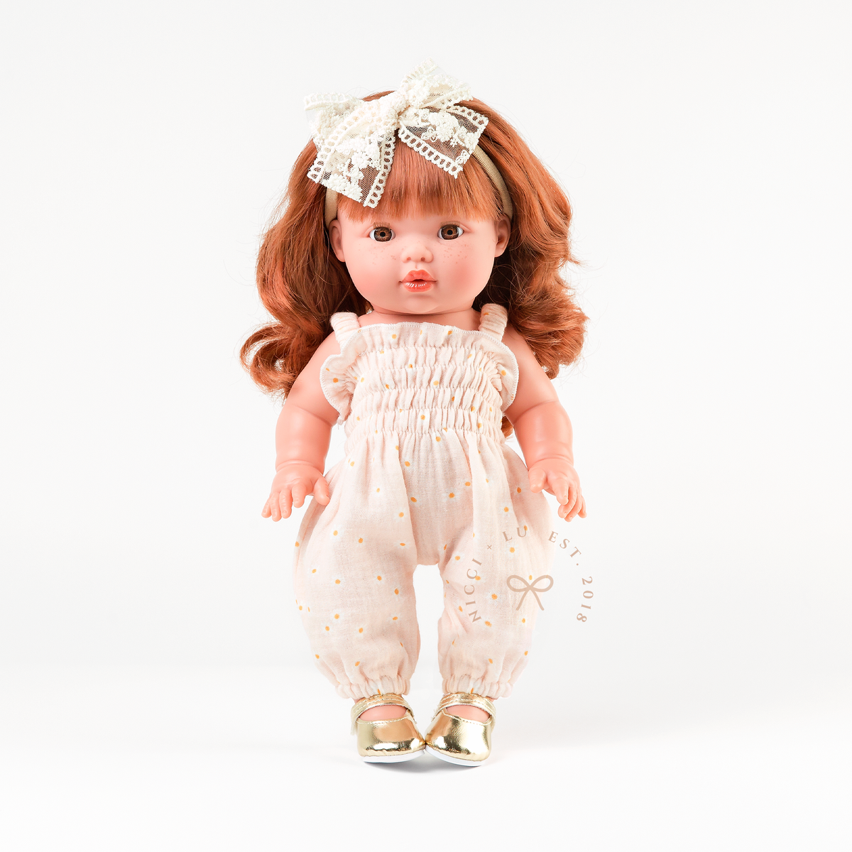 Mini Colettos Sophia wearing the Florence Smocked Jumpsuit in Daisy Print Muslin with Gold Mary Jane shoes.