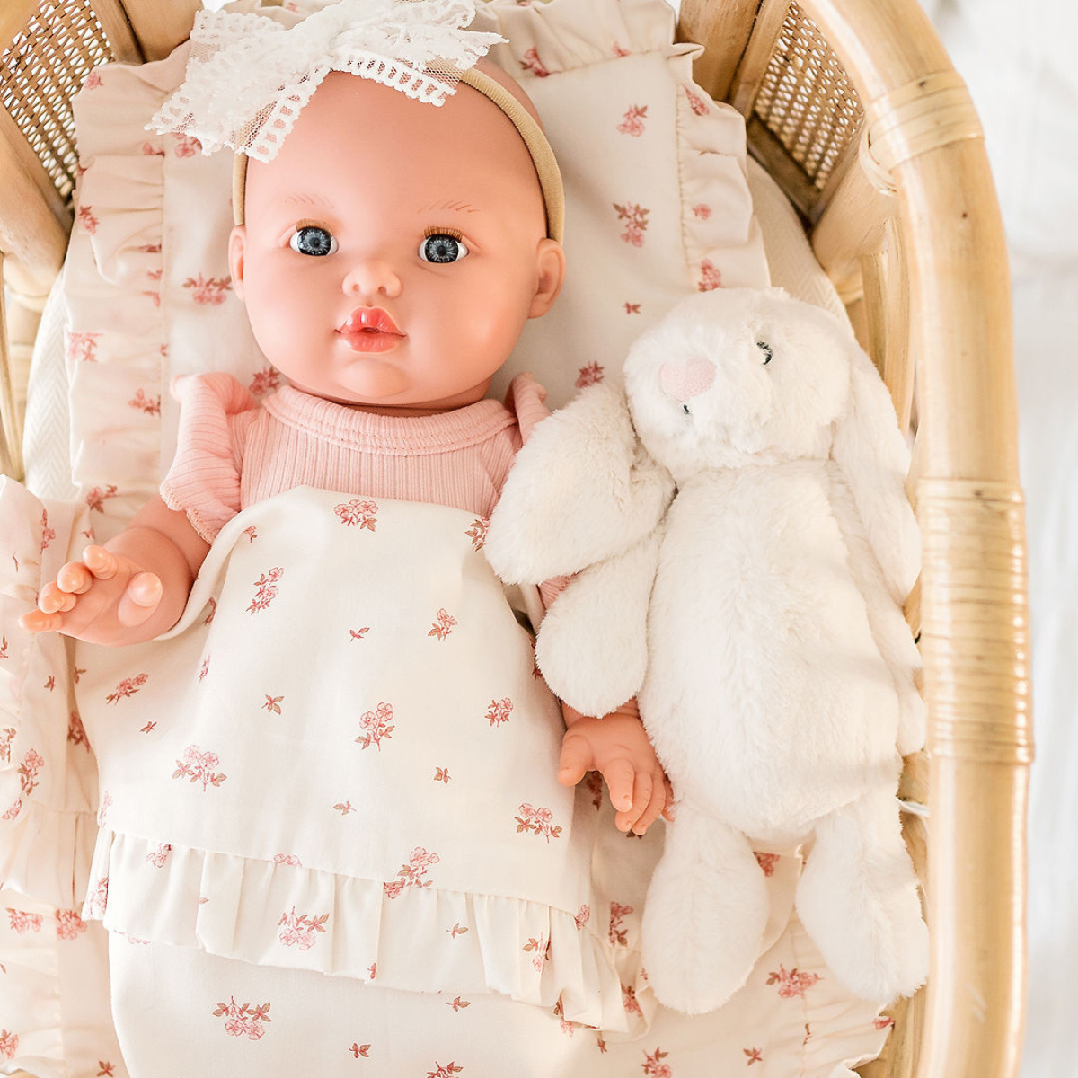 Mila Mini Coletto 34cm doll in a Rose Pink outfit with a white bunny in a Rattan Bassinet basket