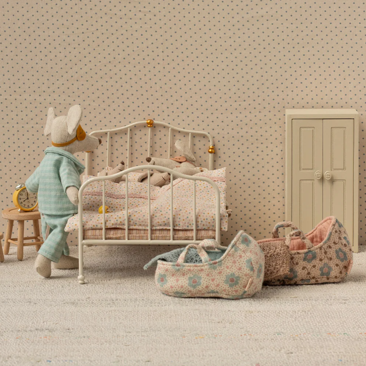 Miniature bedroom scene with a baby Maileg Mice, Mum and Dad Mice with Rose and Blue Carry cot on the side of a bed