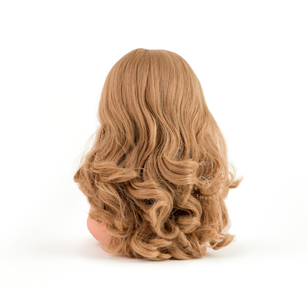 The back view of Lyla highlights her beautiful long blonde hair, featuring soft waves and curls cascading down her back. This photograph showcases the hairstyle and hair length of the 34cm Mini Colettos Lyla doll.