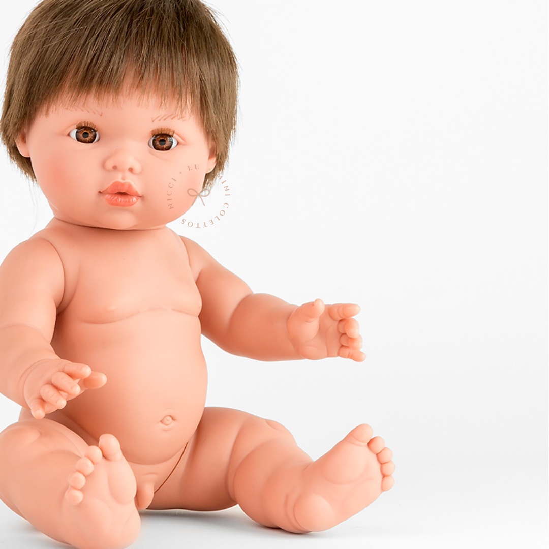 Close-up of Mini Colettos Rafael seated undressed, showing his short light brown hair, arms and legs.
