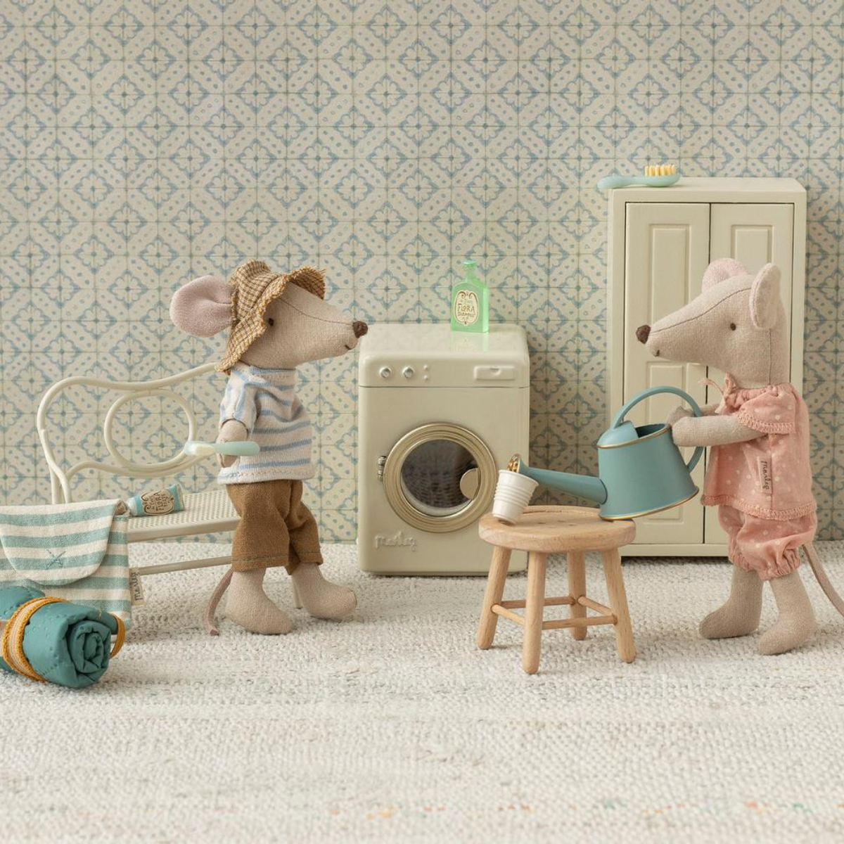 Maileg Mice Big Sister Two toy mice in a room with a washing machine and other items.