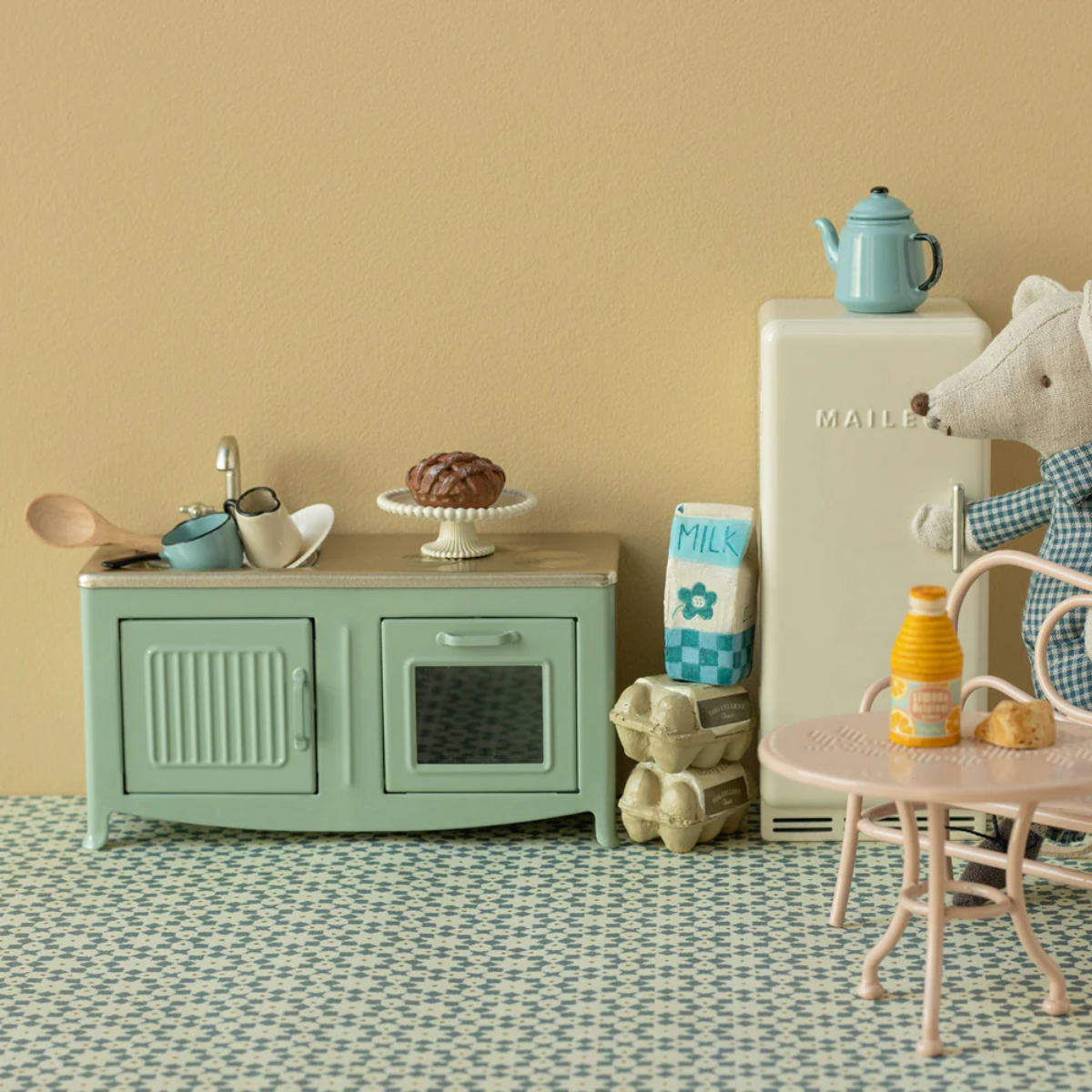 Maileg Miniature Mouse kitchen set in green with a refrigerator, table, and various items on a patterned floor.