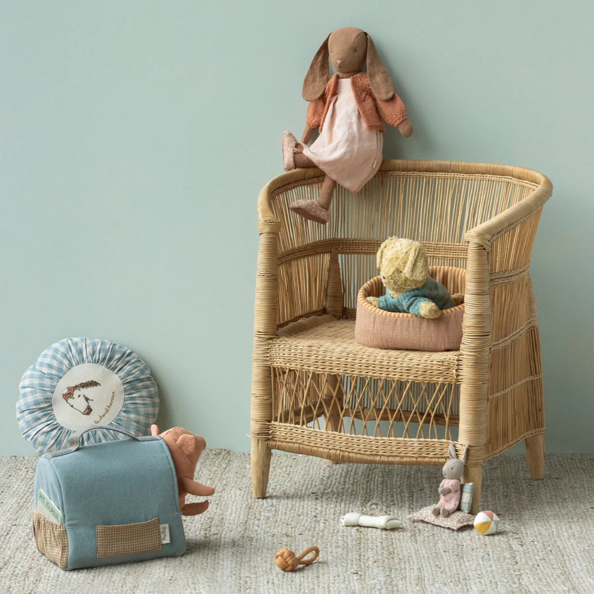 Maileg Puppy Small Soft Sand Wicker chair with toys on a light green wall background