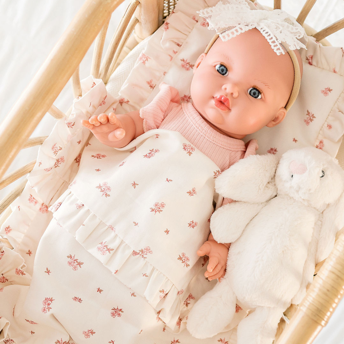 Mila Mini Coletto 34cm  doll in a rattan bassinet with floral bedding and a white  jellycat bunny toy