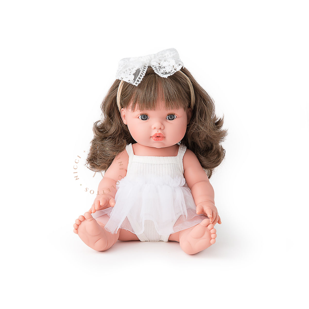 Aria looks adorable dressed in Ivory Tutu Singlet romper with a delicate white lace hair bow. Her beautiful brown curls complete the sweet look, showcasing the 34cm Mini Colettos doll styled for imaginative childhood adventures.