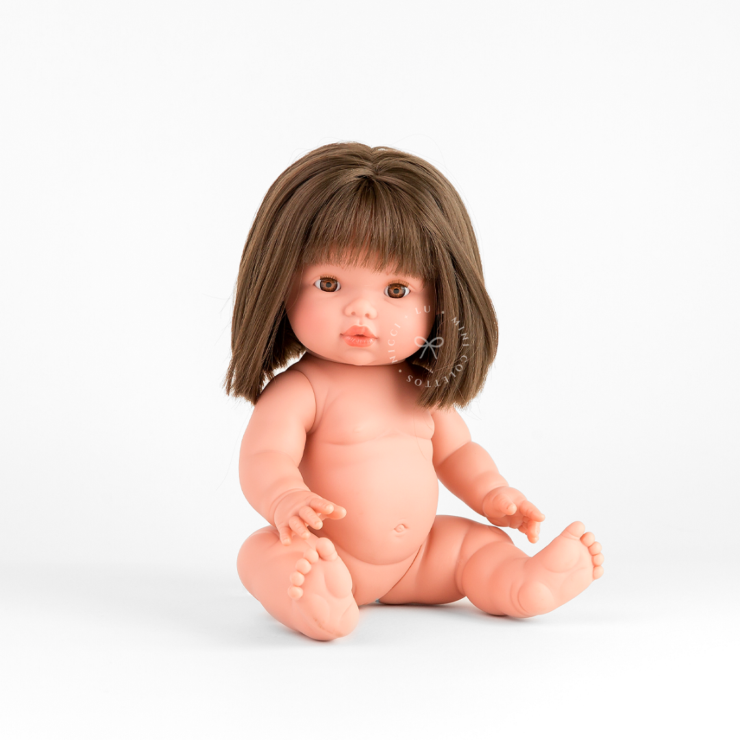 Hazel is beautifully dressed in a soft ivory smocked bubble romper with a delicate pastel bow in her chestnut-brown hair. This styled image showcases how the 34cm Mini Colettos doll can be dressed in charming outfits and accessories for pretend play.
