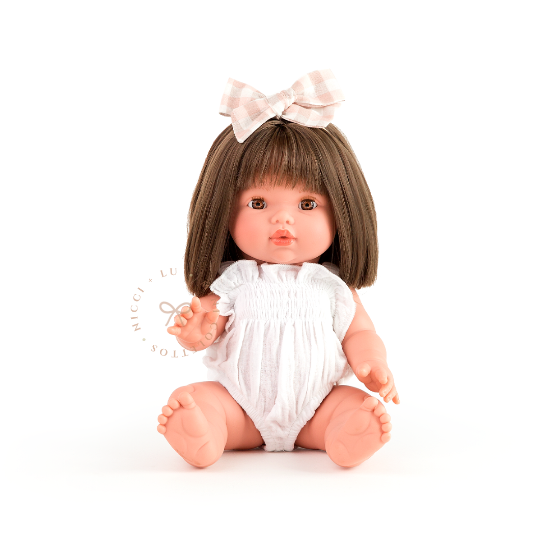 Hazel is beautifully dressed in a soft ivory smocked bubble romper with a delicate pastel bow in her chestnut-brown hair. This styled image showcases how the 34cm Mini Colettos doll can be dressed in charming outfits and accessories for pretend play.