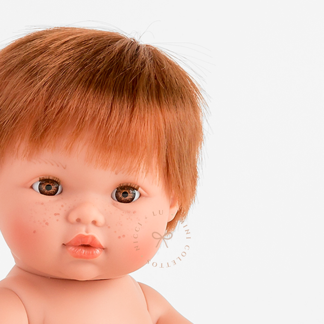 Jasper's sweet freckles, warm brown eyes and neatly styled copper-red hair are beautifully captured in this close-up photograph. His distinctive features give the 34cm Mini Colettos doll a charming appearance.