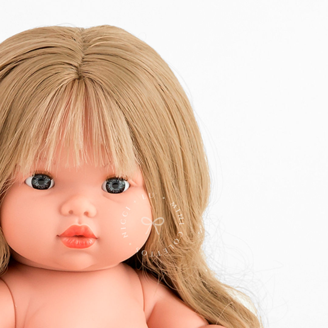Lyla's expressive blue-grey eyes, delicate facial features and beautiful blonde fringe are captured in this detailed portrait. Her long, softly curled hair gives the 34cm Mini Colettos doll a timeless appearance.
