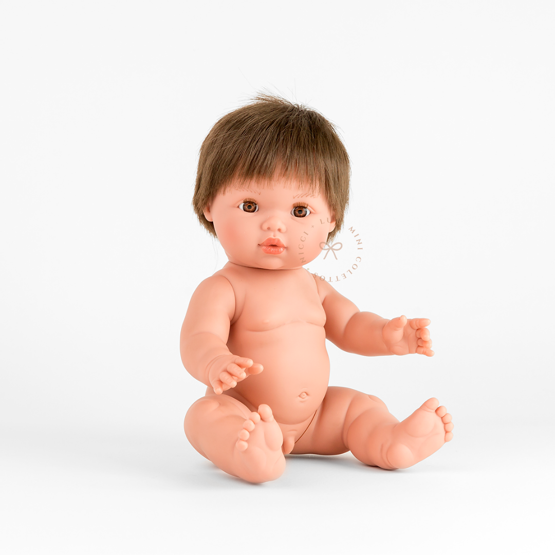 Mini Colettos Rafael doll seated undressed, with short light brown hair, a fringe and warm brown eyes.
