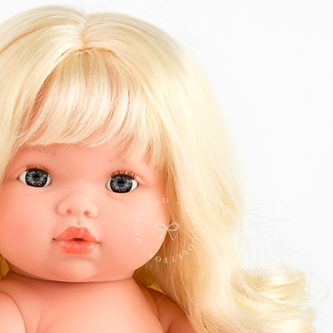 Sage's beautiful blue-grey eyes, delicate facial features and soft blonde fringe are captured in this close-up photograph. Her long golden curls give this 34cm Mini Colettos doll a distinctive, charming appearance.