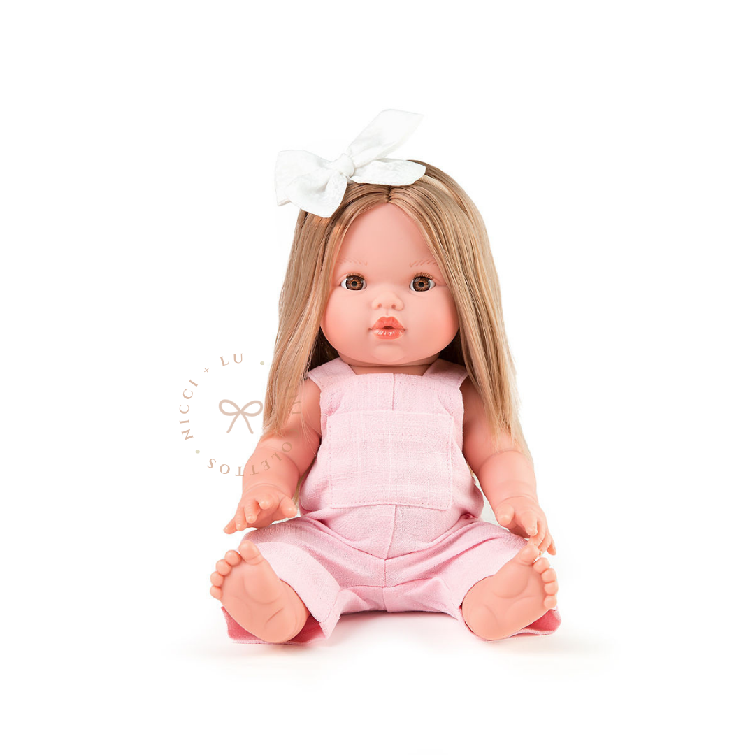 Sandra looks sweet wearing a pale pink romper paired with a delicate white hair bow. Her long, straight blonde hair complements this soft pastel outfit, showing how beautifully the 34cm Mini Colettos doll can be dressed and accessorised.