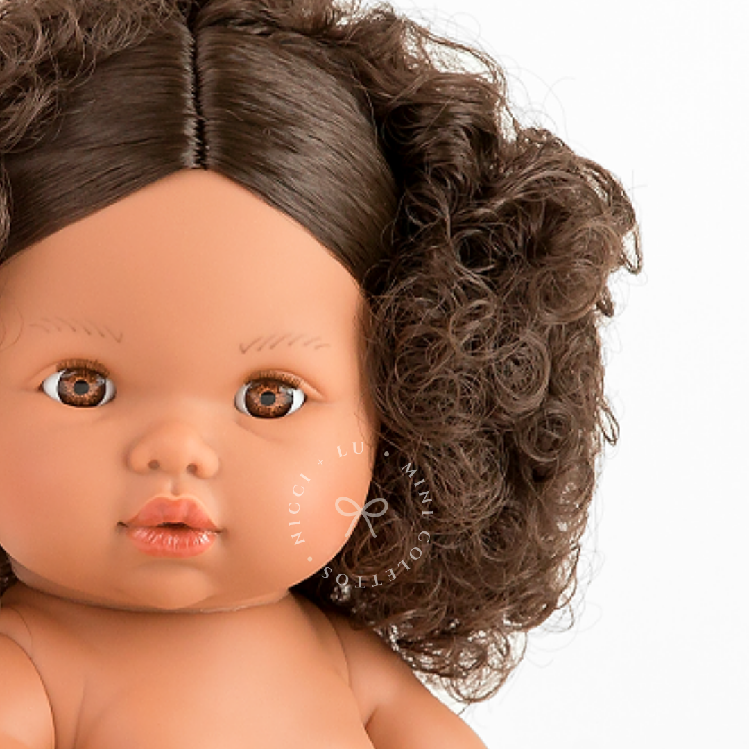 Discover Zaara's sweet facial details, from her expressive brown eyes and delicate lips to her gorgeous, textured dark brown curls. This close-up highlights the lifelike features of the 34cm Mini Colettos doll.