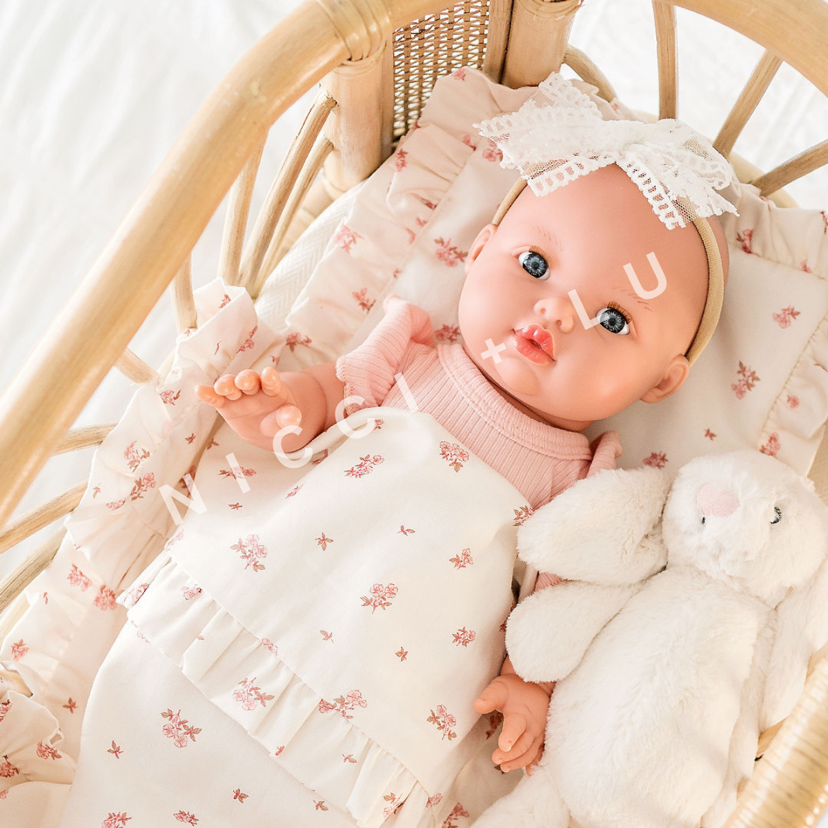 Mini Colettos 34cm Baby doll Mila wrapped in a floral comforter set with a Jellycat bunny, wearing a lace headband