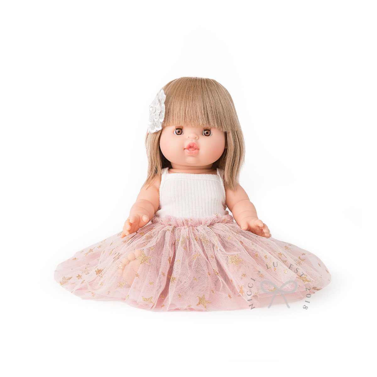Doll with blonde hair, white top, and pink skirt on a white background