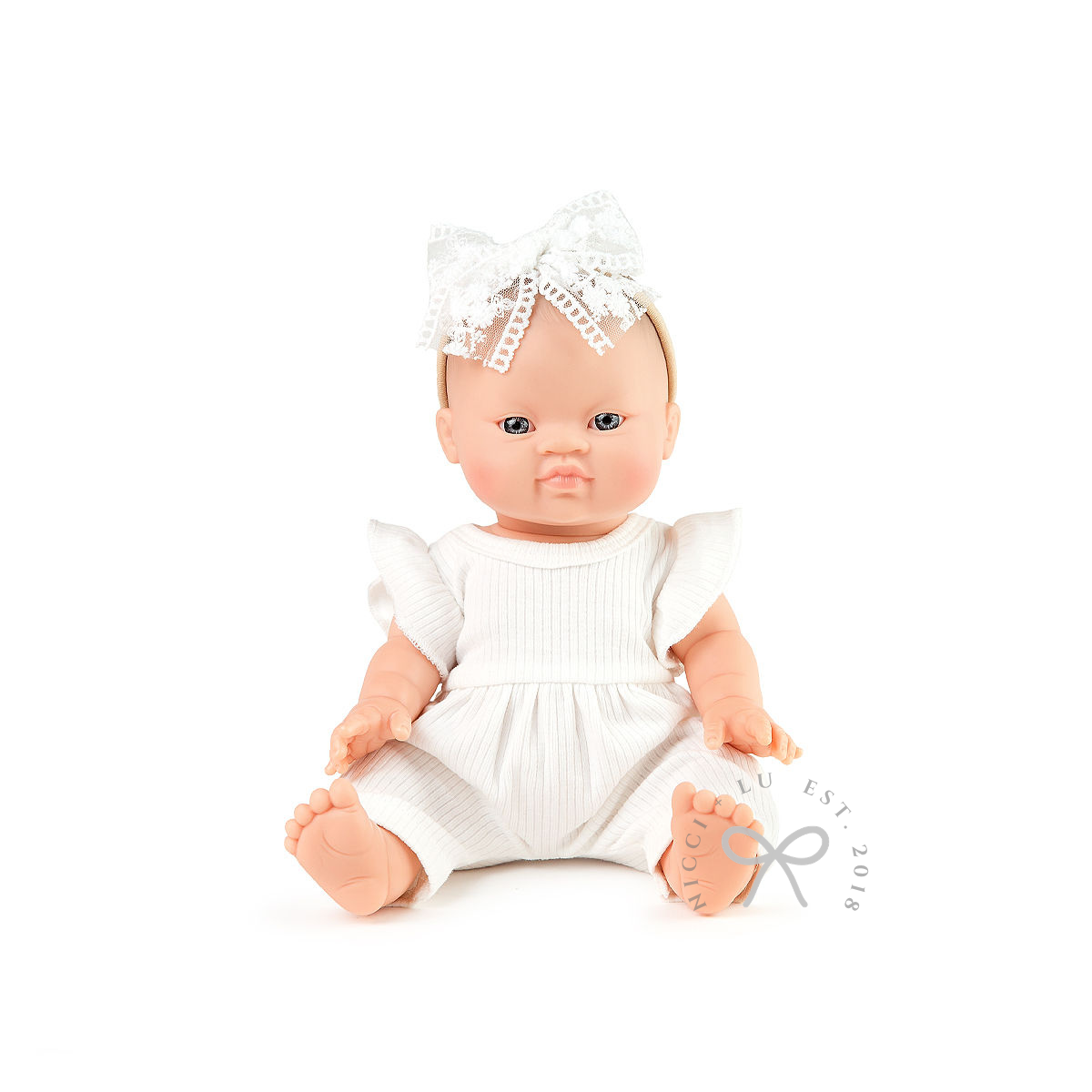 Baby doll wearing a white outfit and headband on a white background