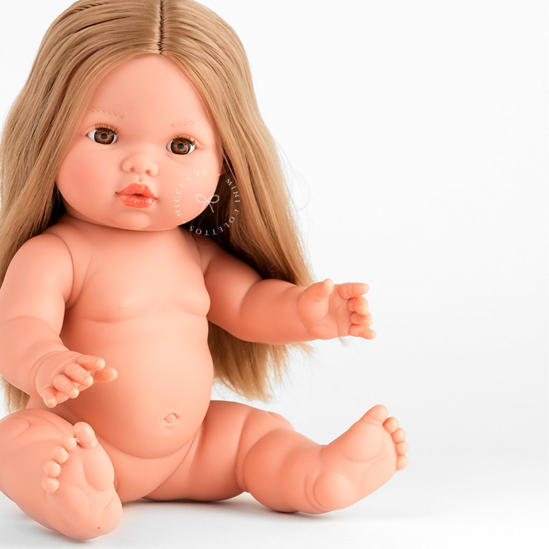 Close-up of Mini Colettos Sandra seated undressed, showing her long blonde hair, arms and legs.
