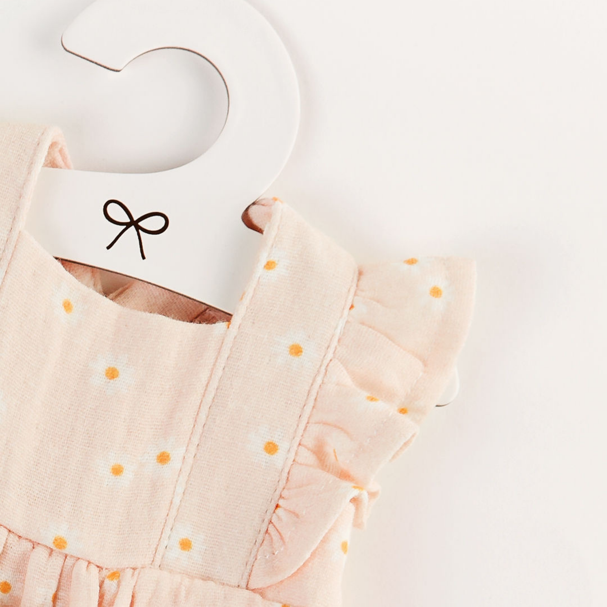 Flat lay of the Elodie Frilled Bubble Playsuit in Daisy Print Muslin for 34cm dolls.