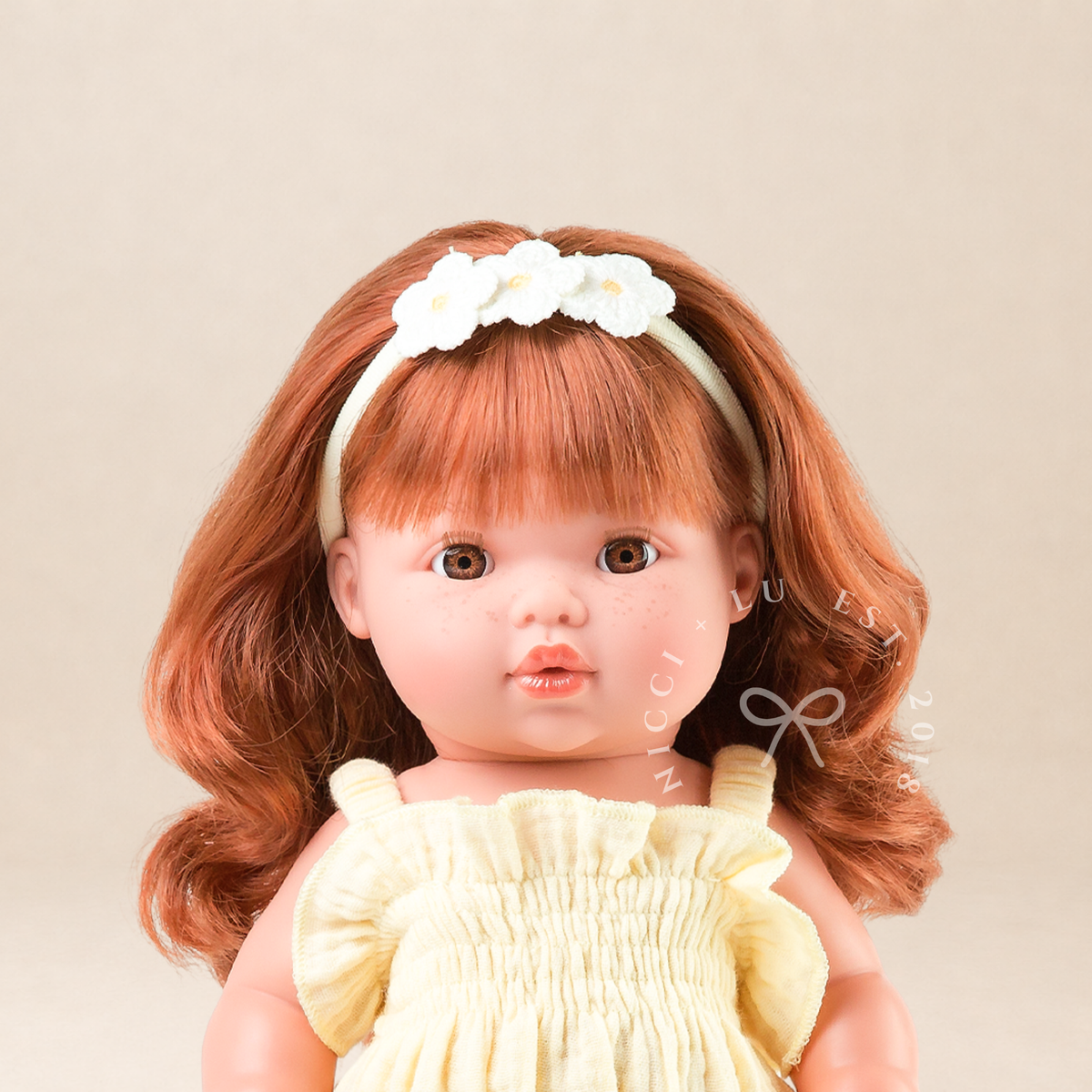 Portrait of Mini Colettos Sophia wearing the Olivia Smocked Bubble Romper in Lemon Butter Muslin with a floral headband.