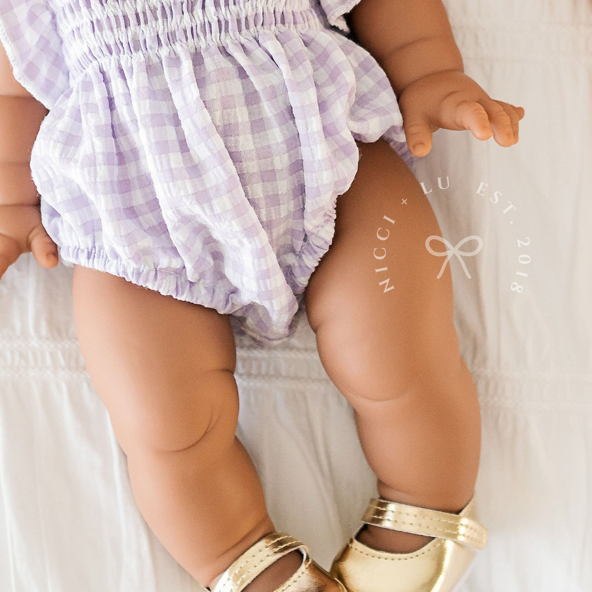Close-up of the Olivia Smocked Bubble Romper in Lilac Gingham showing the soft cotton fabric and gathered leg openings.