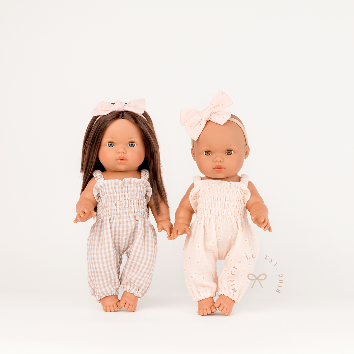 Mini Colettos Isabel wearing the Florence Smocked Jumpsuit in Beige Gingham beside Alba wearing the Daisy Print Muslin Florence Smocked Jumpsuit.