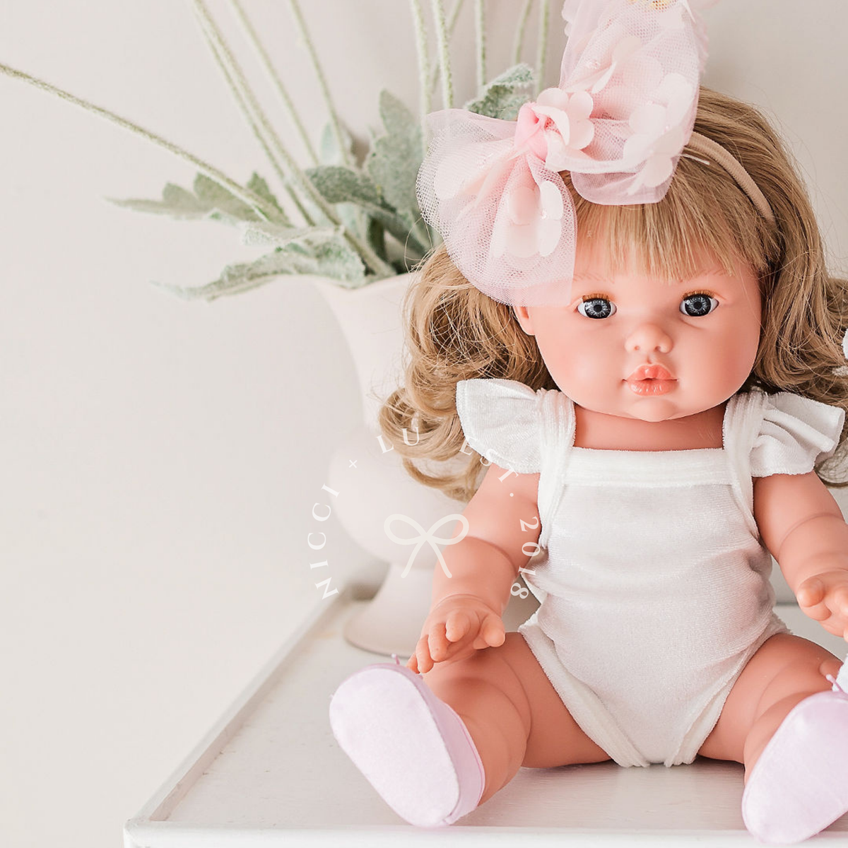 Mini Colettos Kate wearing the Ivory Frilled Velvet Singlet Bodysuit with a delicate floral arrangement.