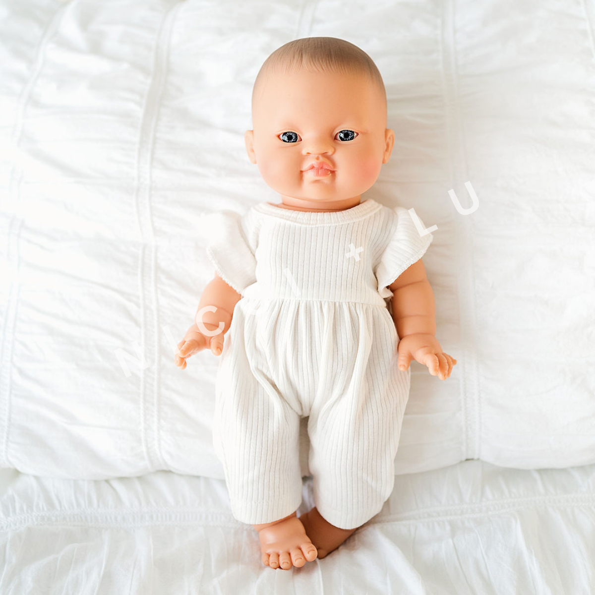 Baby doll wearing a white outfit and headband on a white background
