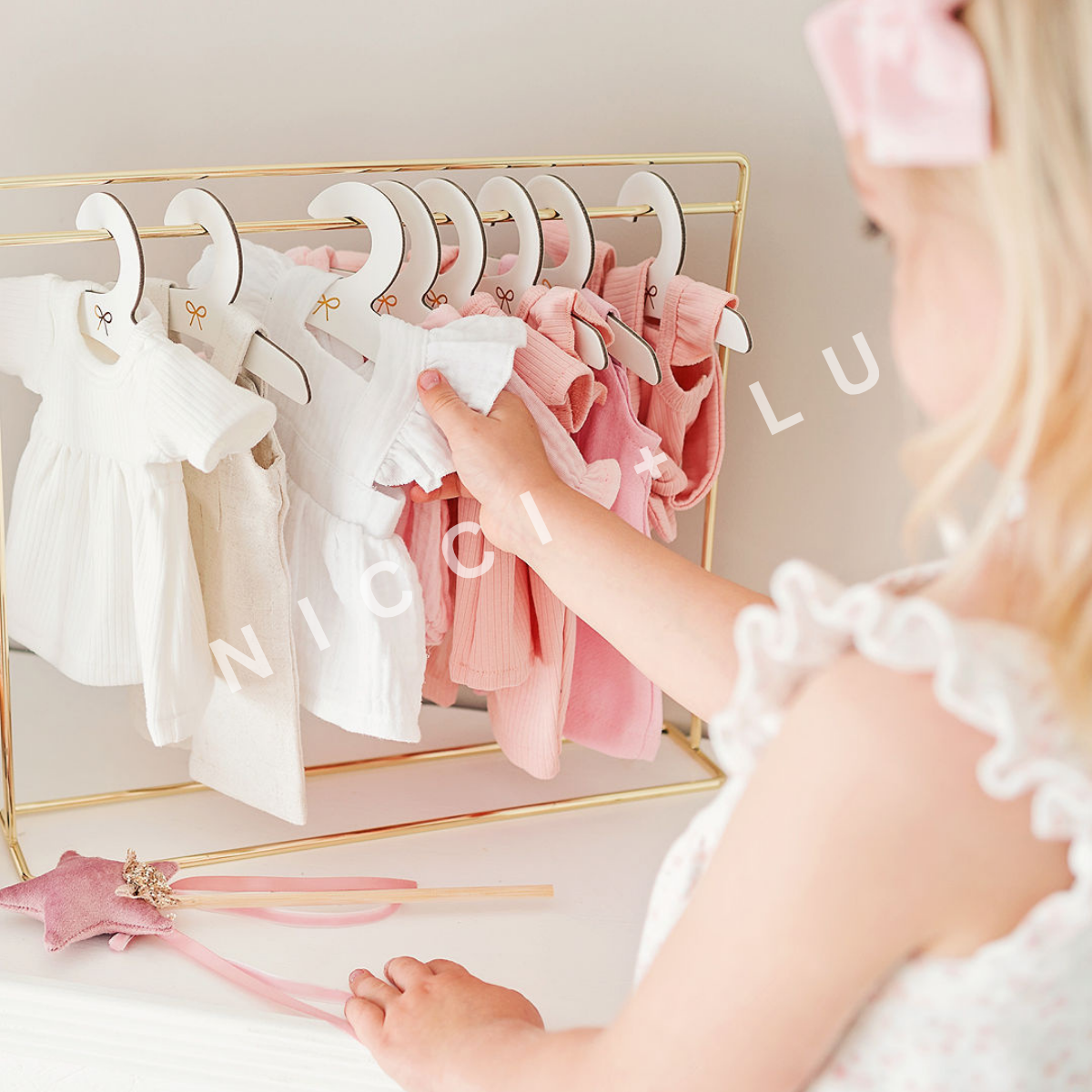 Gold metal clothing rail for doll clothing rack on a white background