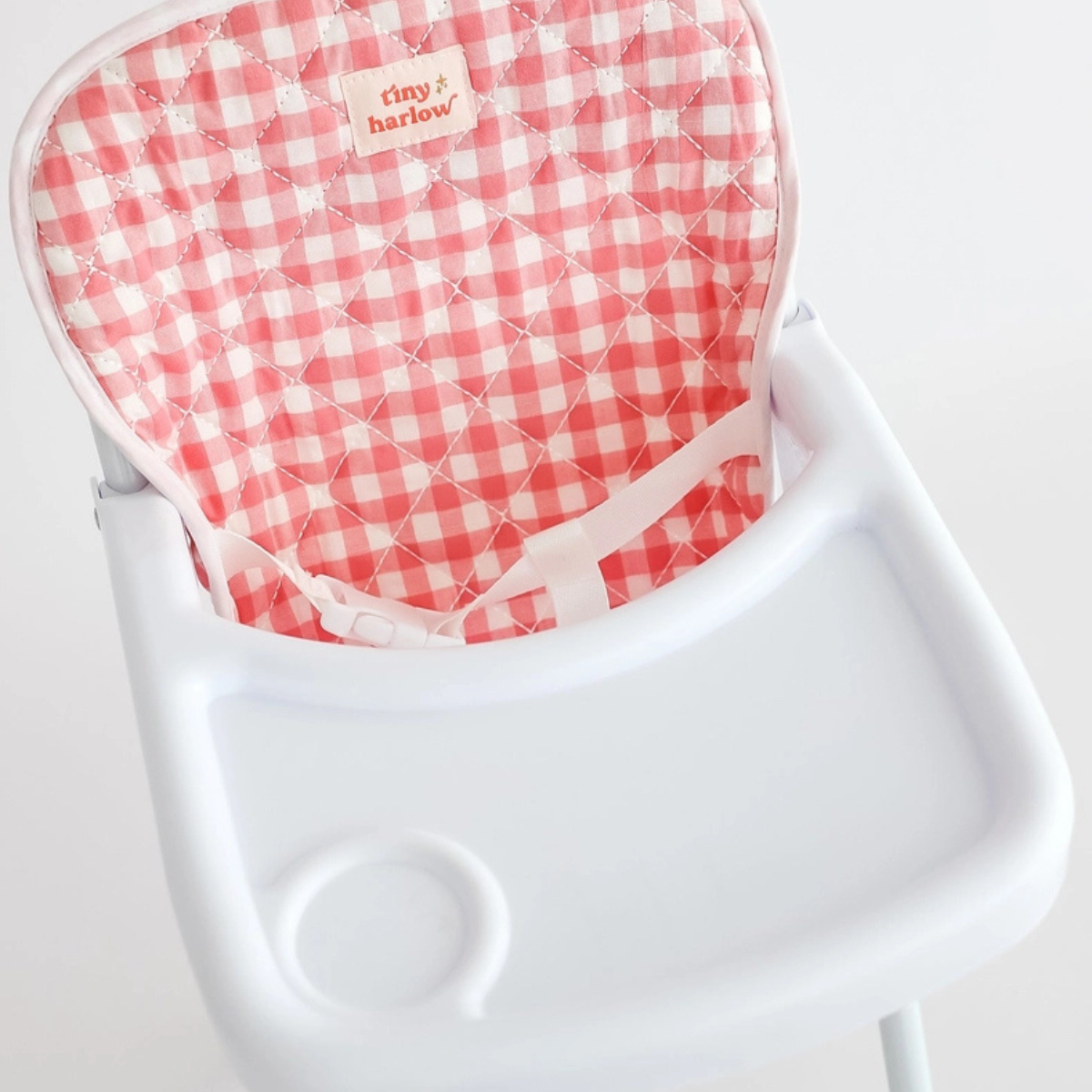 Close-up of the pink gingham seat and tray on the Tiny Harlow doll highchair